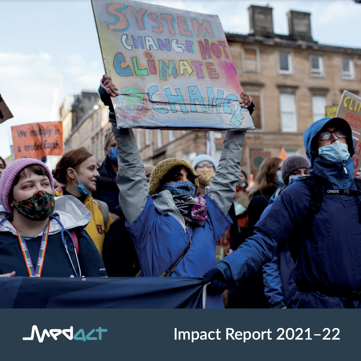 Medact Impact Report 2021-22 cover: Cover image features health workers in scrubs, facemasks, marching with placards. One placard reads in colourful letters: 'System Change Not Climate Change'.