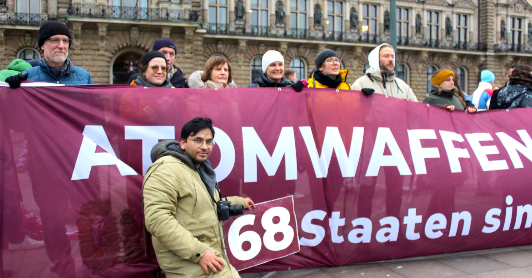 Bimal in front of a banner at the demonstration in Hamburg