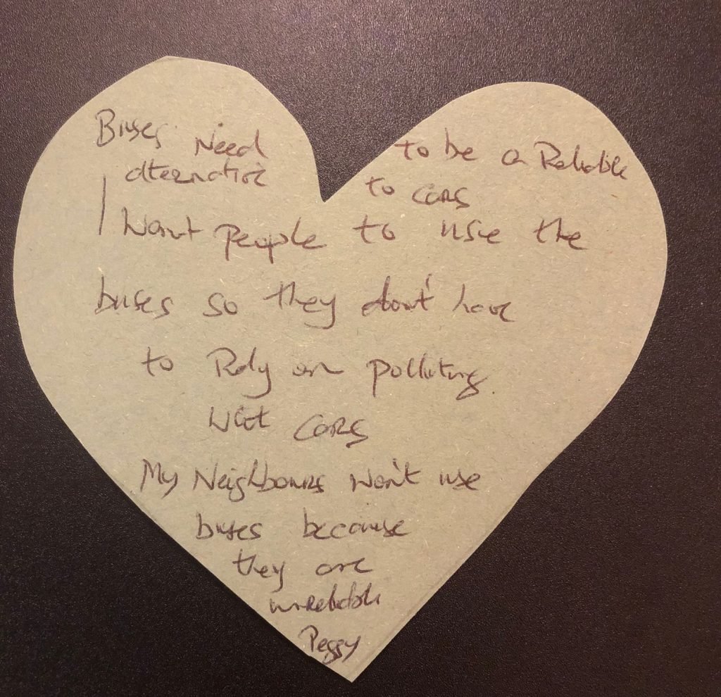 A heart-shaped piece of paper with handwriting that reads: "Buses need to be a reliable alternative to cars. I want people to use buses so they don't have to rely on polluting cars. My neighbours don't use buses because they are unreliable. – Peggy"