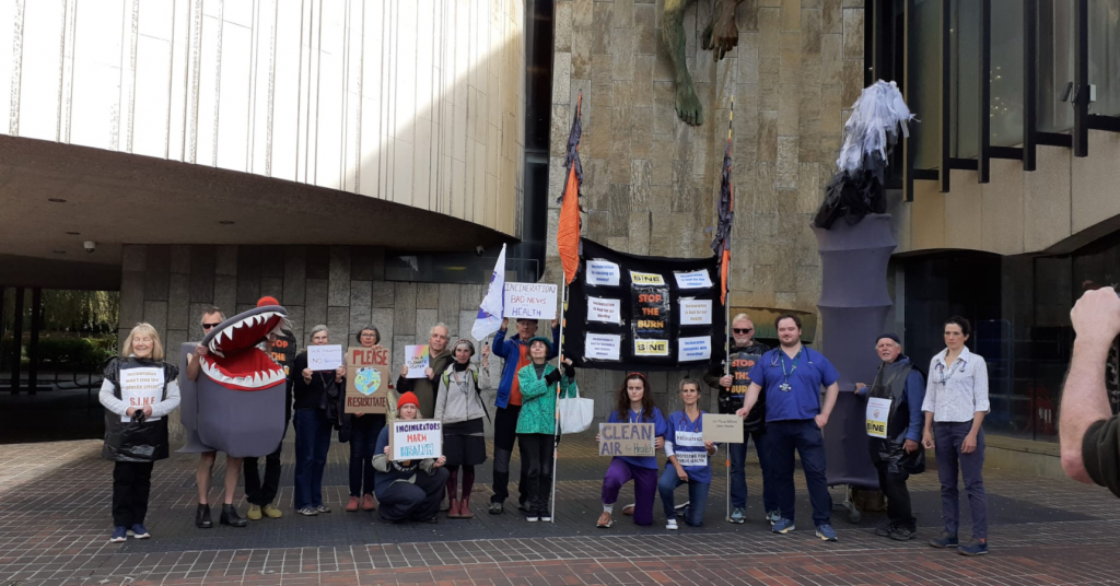 Protestors including Health workers in a row outside Newcastle Civi Centre, holding signs like "Clean Air for Health", and "Incinerators Harm Health"