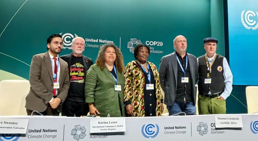 Peace and anti-nuclear activists standing on a stage at a COP29 press conference.