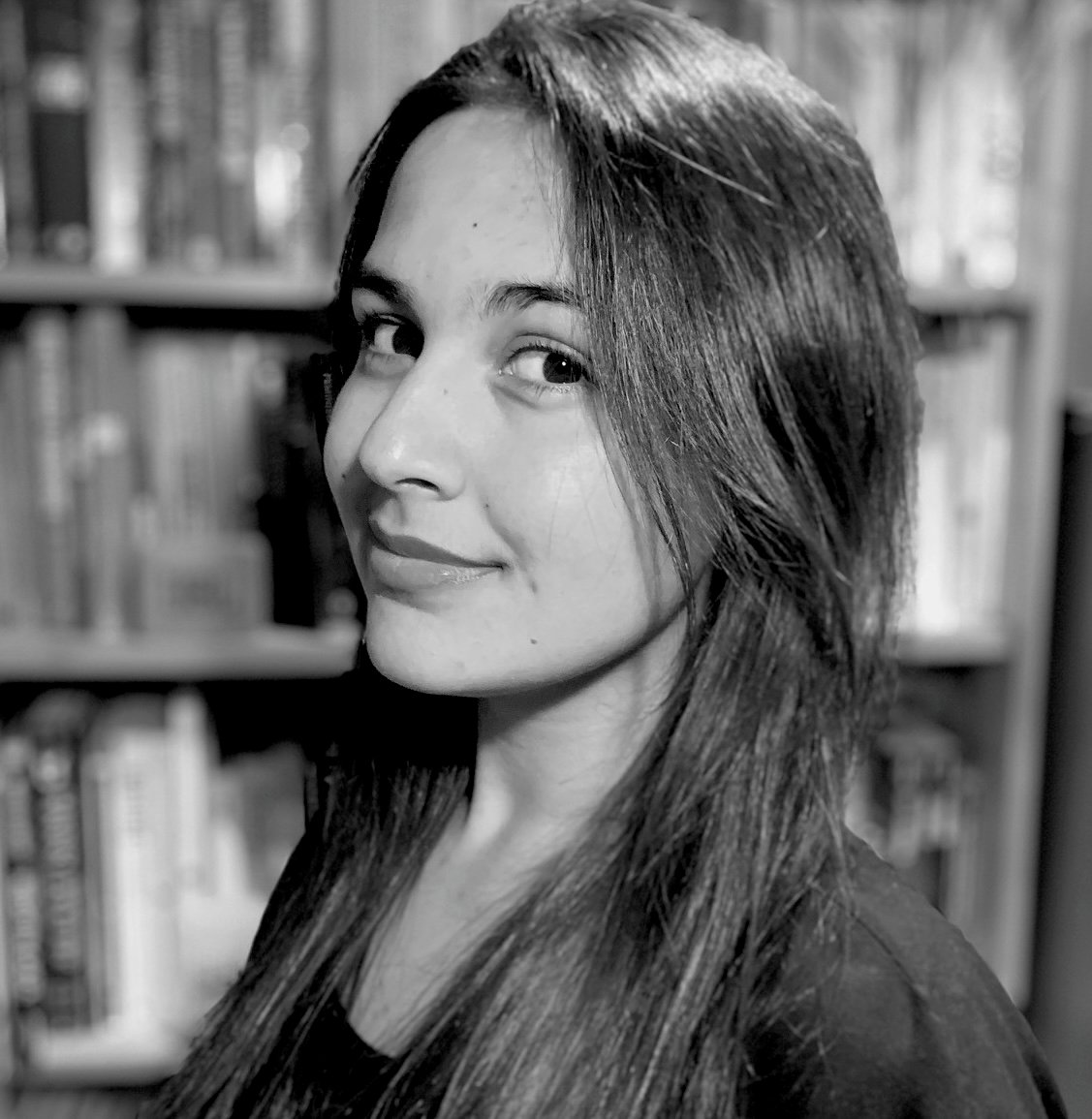 Anna Peiris, a black & white photo of a woman in profile with straight hair, smiling, looking at the camera