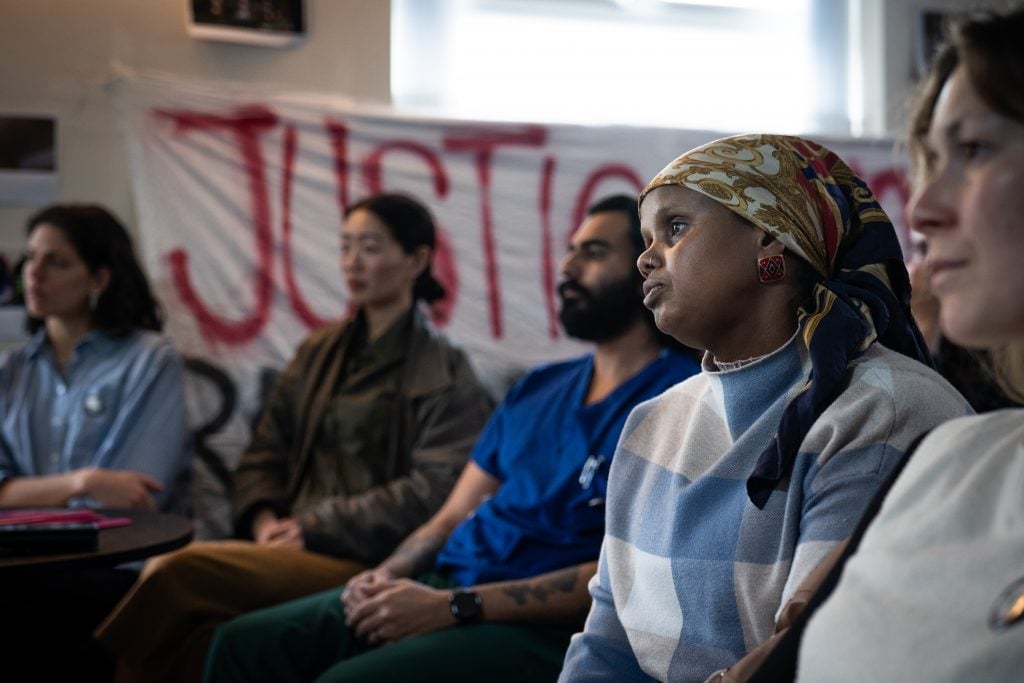 ACORN member and Barton House resident Fadumo sitting in the crowd at the meeting