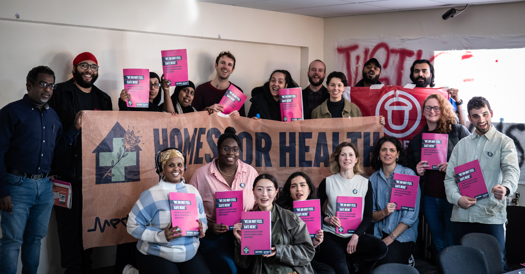 Medact Bristol and Barton House residents in a group photo around a 'Homes for Health' banner and each holding up a pink report