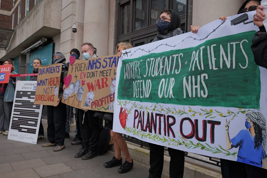 Protestors hold a banner reading 'Workers, Students, Patients defend our NHS: Palantir Out'